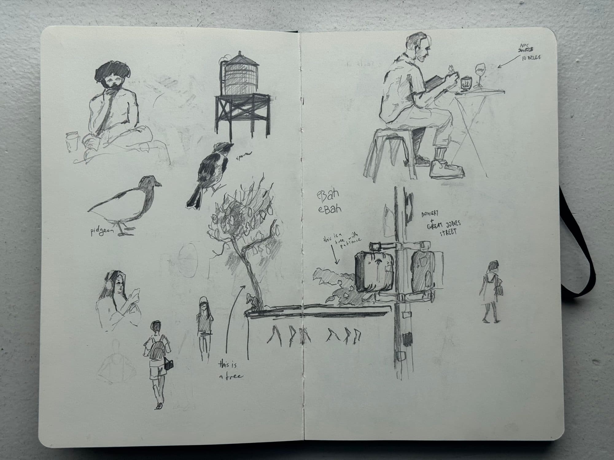 Sketchbook spread of New York observational drawings: a water tower, pigeons and a sparrow, passersby, a tree, and a man sketching at a café table.